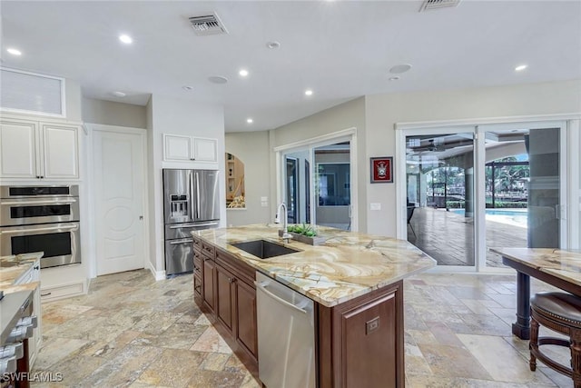 1658 Mcilvaine Ct, Marco Island, FL 34145 - kitchen featuring a sink, stainless steel appliances, stone tile flooring, light stone countertops, and arched walkways
