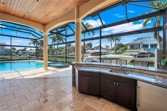1658 Mcilvaine Ct, Marco Island, FL 34145 - view of patio / terrace featuring a sink, glass enclosure, an outdoor kitchen, a water view, and a pool with connected hot tub
