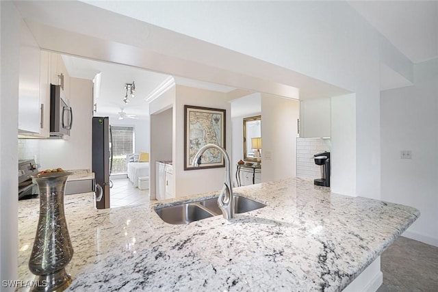 1250 Yesica Ann Cir Unit E106, Naples, FL 34110 - kitchen with appliances with stainless steel finishes, a peninsula, tile patterned floors, a fireplace, and ornamental molding