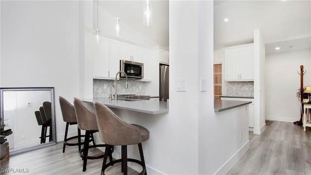 9640 Victoria Ln Unit C308, Naples, FL 34109 - kitchen with appliances with stainless steel finishes, a kitchen bar, decorative backsplash, light wood finished floors, and recessed lighting