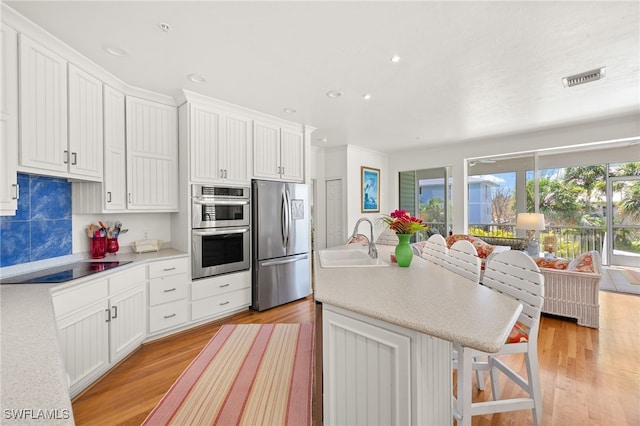 11533 Andy Rosse Ln, Captiva, FL 33924 - kitchen featuring appliances with stainless steel finishes, a sink, light wood-type flooring, light countertops, and a kitchen island with sink