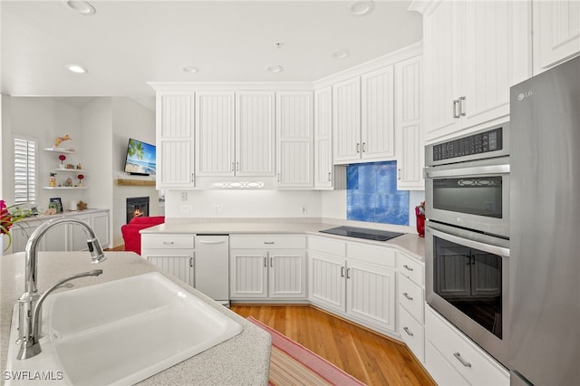 11533 Andy Rosse Ln, Captiva, FL 33924 - kitchen featuring refrigerator, a sink, stainless steel double oven, black electric cooktop, and light wood-style floors