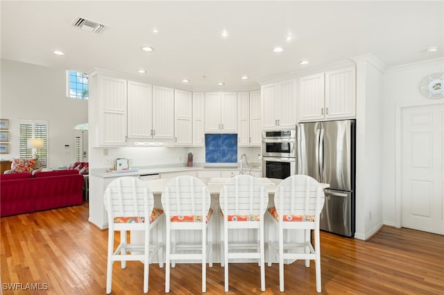 11533 Andy Rosse Ln, Captiva, FL 33924 - kitchen featuring stainless steel appliances, light countertops, white cabinets, recessed lighting, and a kitchen bar