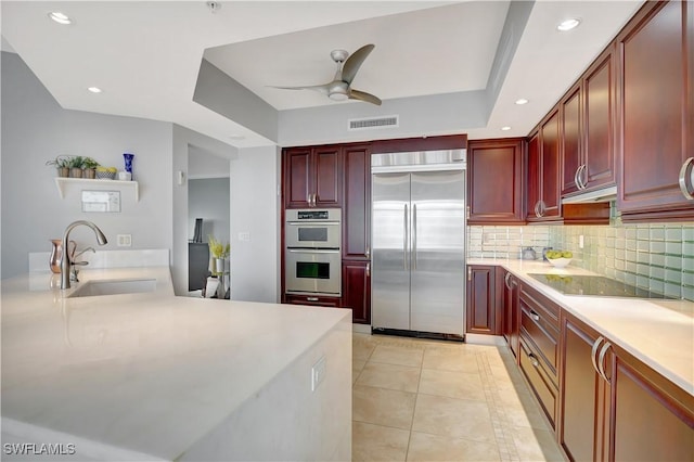 1050 Borghese Ln Unit 801, Naples, FL 34114 - kitchen with stainless steel appliances, reddish brown cabinets, a sink, decorative backsplash, and light countertops