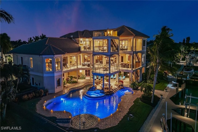 1547 Caxambas Ct, Marco Island, FL 34145 - back of property with a balcony, boat lift, a patio, a pool with connected hot tub, and stucco siding