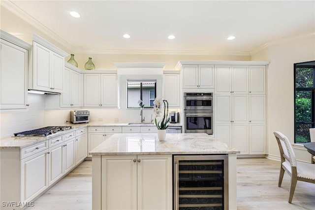 20081 Chapel Trce, Estero, FL 33928 - kitchen with beverage cooler, stainless steel appliances, light wood-type flooring, backsplash, and a kitchen island