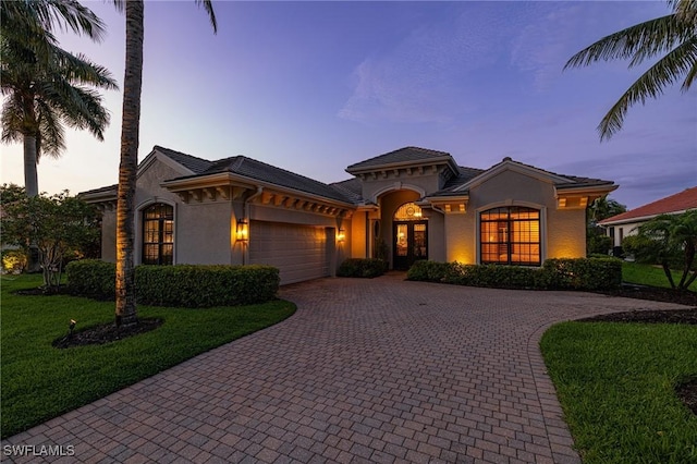 20081 Chapel Trce, Estero, FL 33928 - mediterranean / spanish-style home featuring an attached garage, stucco siding, decorative driveway, and a yard