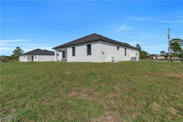 1059 Brenton Ave, Lehigh Acres, FL 33974 - view of side of property with a yard, stucco siding, and central AC unit