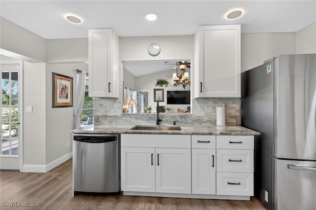 24769 Paradise Rd, Bonita Springs, FL 34135 - kitchen featuring stainless steel appliances, white cabinetry, tasteful backsplash, light stone countertops, and vaulted ceiling