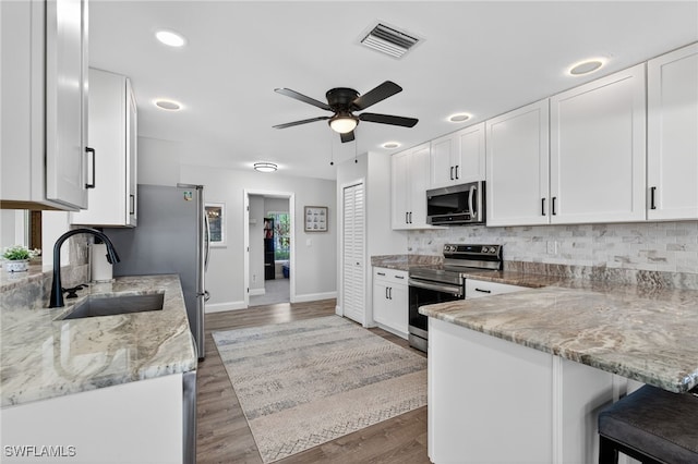24769 Paradise Rd, Bonita Springs, FL 34135 - kitchen with stainless steel appliances, white cabinetry, ceiling fan, a breakfast bar, and recessed lighting