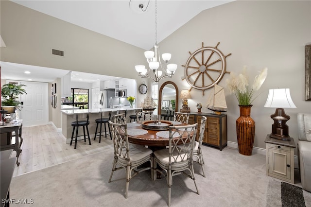 15444 Admiralty Cir Unit 10, North Fort Myers, FL 33917 - dining area featuring light carpet, baseboards, a chandelier, and high vaulted ceiling