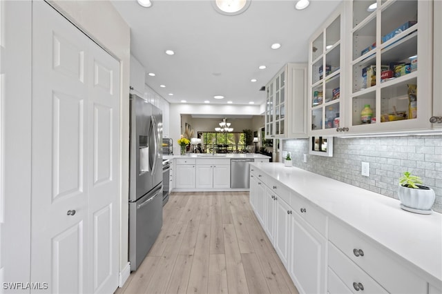 15444 Admiralty Cir Unit 10, North Fort Myers, FL 33917 - kitchen featuring appliances with stainless steel finishes, white cabinets, light wood-type flooring, decorative backsplash, and a sink