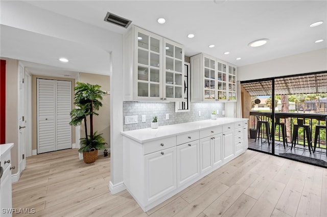 15444 Admiralty Cir Unit 10, North Fort Myers, FL 33917 - kitchen with light wood-style floors, decorative backsplash, baseboards, light countertops, and glass insert cabinets