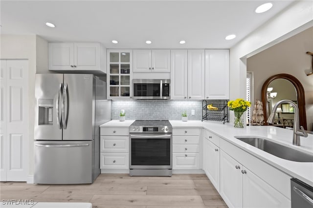 15444 Admiralty Cir Unit 10, North Fort Myers, FL 33917 - kitchen with appliances with stainless steel finishes, a sink, tasteful backsplash, light wood-style flooring, and glass insert cabinets