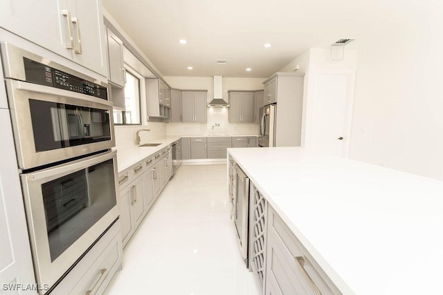 717 Calvin Ave, Lehigh Acres, FL 33972 - kitchen featuring stainless steel appliances, wall chimney range hood, a sink, gray cabinets, and recessed lighting