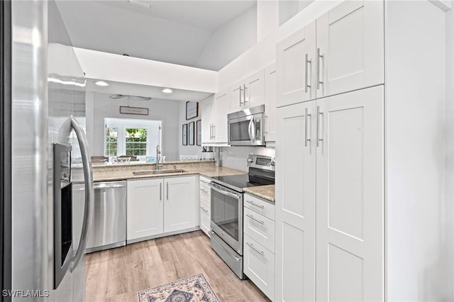 10811 Breaker Ln, Naples, FL 34109 - kitchen featuring stainless steel appliances, a sink, white cabinets, light stone countertops, and light wood-style flooring