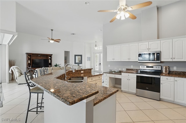 5408 SW 26th Ct, Cape Coral, FL 33914 - kitchen featuring stainless steel appliances, ceiling fan, light tile patterned floors, a breakfast bar, and white cabinetry