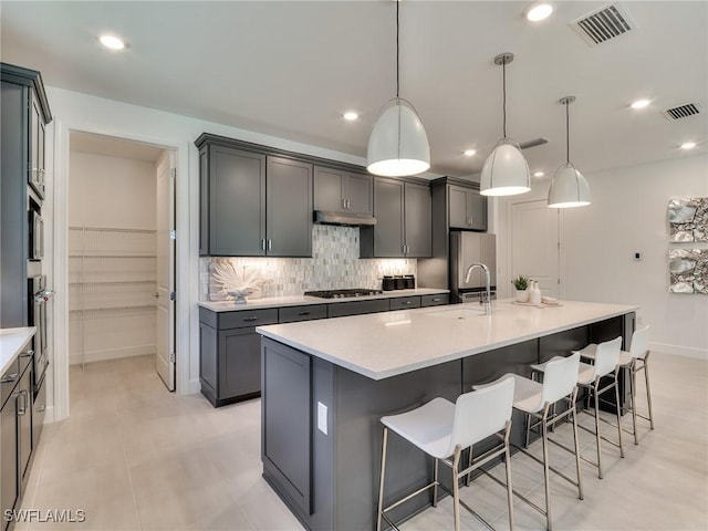 17304 Green Buttonwood Way N, Fort Myers, FL 33917 - kitchen with a sink, under cabinet range hood, gas stovetop, a large island with sink, and a kitchen breakfast bar