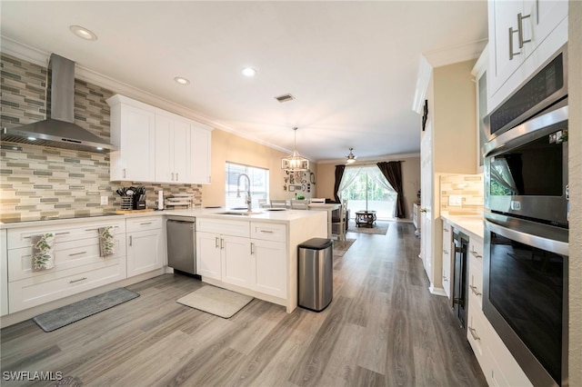 2759 Orange Grove Trl, Naples, FL 34120 - kitchen with ornamental molding, wall chimney range hood, stainless steel appliances, a peninsula, and a sink