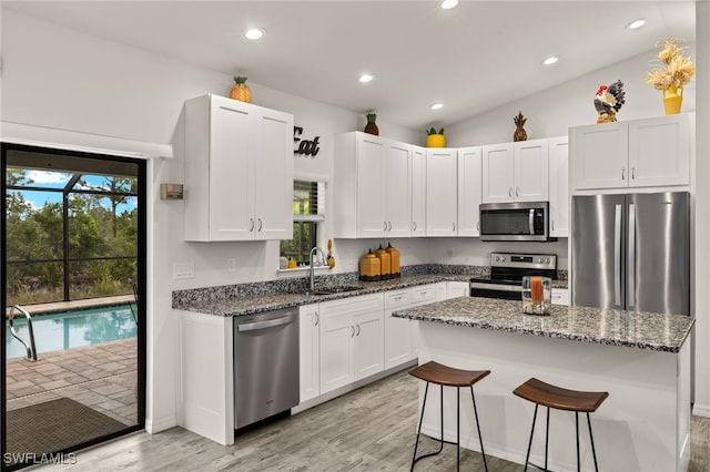 3901 NW 48th Ter, Cape Coral, FL 33993 - kitchen featuring appliances with stainless steel finishes, a sink, light wood-type flooring, dark stone counters, and white cabinets