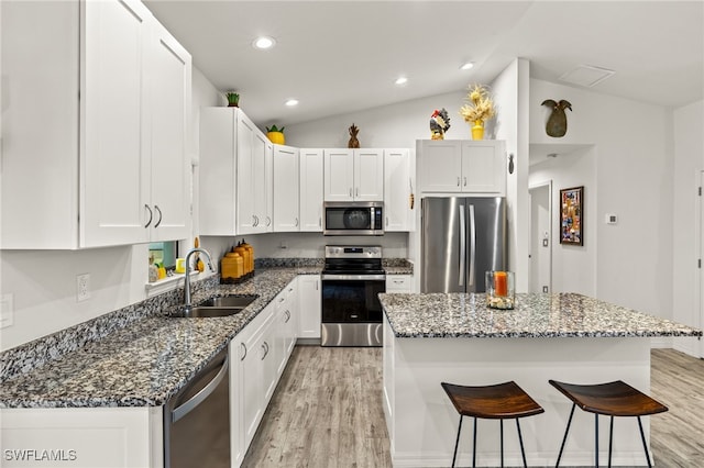 3901 NW 48th Ter, Cape Coral, FL 33993 - kitchen featuring stainless steel appliances, a sink, light wood-style flooring, a breakfast bar area, and vaulted ceiling