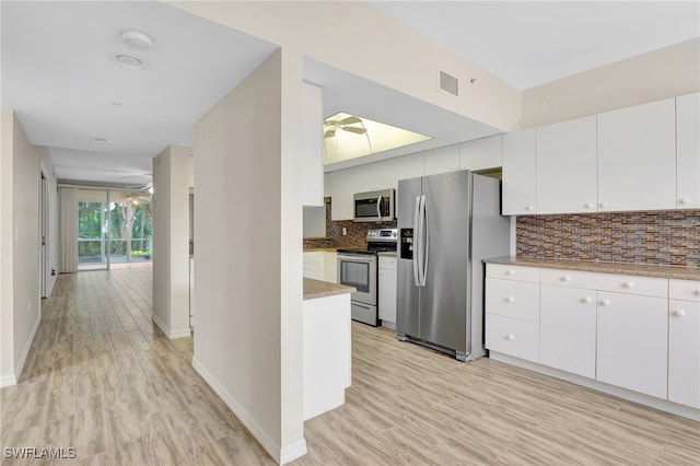 4040 Durango Ct Unit 101, Estero, FL 33928 - kitchen with appliances with stainless steel finishes, tasteful backsplash, white cabinets, light wood finished floors, and light stone counters