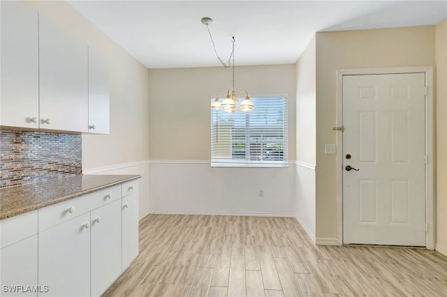 4040 Durango Ct Unit 101, Estero, FL 33928 - kitchen with a chandelier, white cabinetry, tasteful backsplash, light wood-style flooring, and baseboards