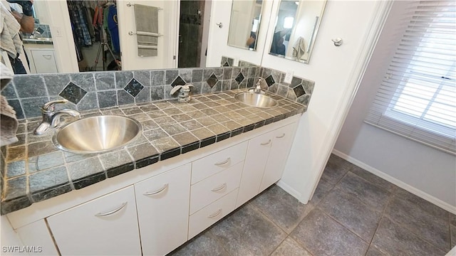2780 39th St SW, Naples, FL 34117 - bathroom featuring double vanity, a walk in closet, and decorative backsplash