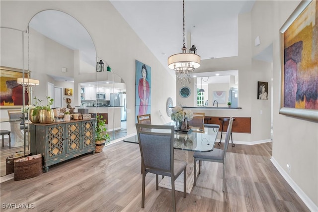 28076 Cavendish Ct Unit 2107, Bonita Springs, FL 34135 - dining area featuring a towering ceiling, a chandelier, wood finished floors, arched walkways, and baseboards