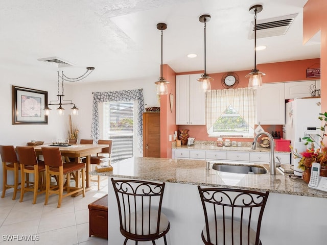 242 Angler Ct, Marco Island, FL 34145 - kitchen featuring a sink, white cabinets, white refrigerator with ice dispenser, and decorative light fixtures