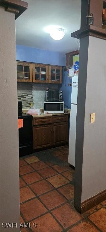 2027 44th St SW, Naples, FL 34116 - kitchen with stove, stainless steel microwave, glass insert cabinets, freestanding refrigerator, and baseboards