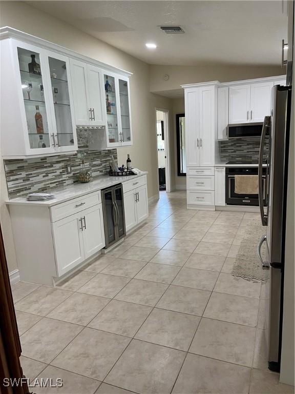 260 29th St SW, Naples, FL 34117 - kitchen with beverage cooler, appliances with stainless steel finishes, backsplash, light countertops, and white cabinets