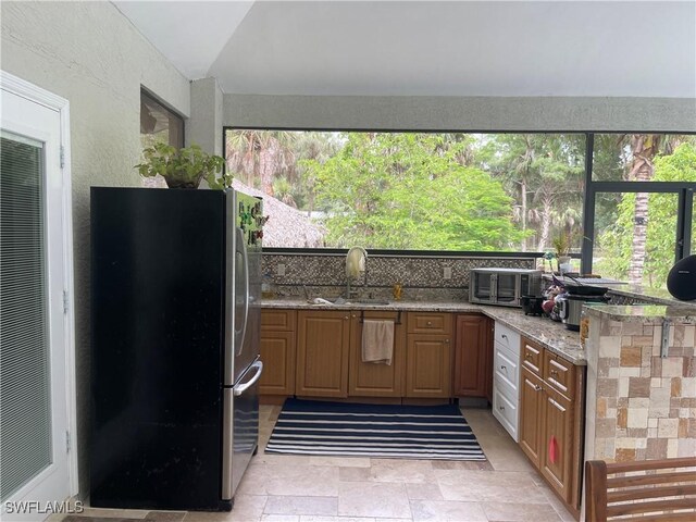260 29th St SW, Naples, FL 34117 - kitchen with freestanding refrigerator, vaulted ceiling, light stone countertops, light stone finish floors, and a sink