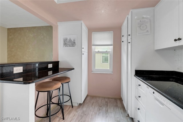1155 Sandpiper St Unit D4, Naples, FL 34102 - kitchen with light wood-type flooring, white cabinetry, white dishwasher, a kitchen breakfast bar, and dark stone countertops