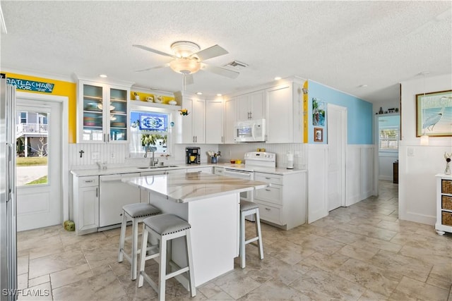 2839 Janet St, Matlacha, FL 33993 - kitchen with white appliances, a breakfast bar area, a textured ceiling, white cabinetry, and a ceiling fan