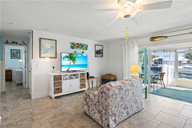 2839 Janet St, Matlacha, FL 33993 - living area with ceiling fan, a textured ceiling, and wainscoting