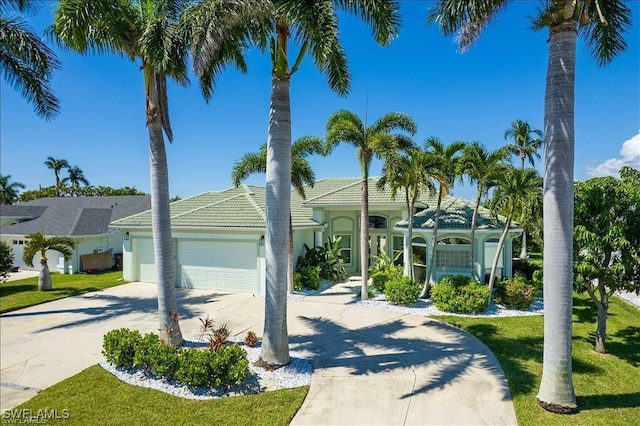 623 SW 56th St, Cape Coral, FL 33914 - mediterranean / spanish home featuring concrete driveway, an attached garage, a front yard, stucco siding, and a tiled roof