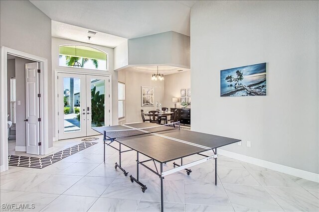623 SW 56th St, Cape Coral, FL 33914 - playroom with light marble finish floors, french doors, a towering ceiling, baseboards, and a chandelier