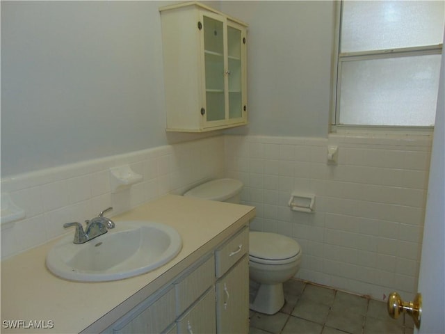 100 Waterview Ave, Lehigh Acres, FL 33936 - bathroom with tile walls, toilet, vanity, tile patterned flooring, and wainscoting