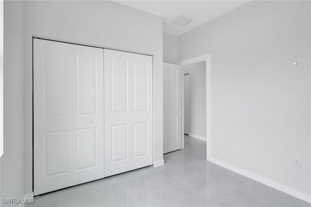 1072 Norton Ave S, Lehigh Acres, FL 33974 - unfurnished bedroom featuring a closet, baseboards, and light tile patterned floors