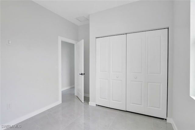1072 Norton Ave S, Lehigh Acres, FL 33974 - unfurnished bedroom featuring a closet, baseboards, and light tile patterned floors