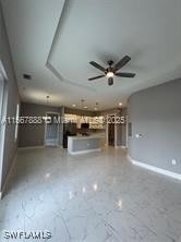 426 Mercedes Ct, Lehigh Acres, FL 33972 - unfurnished living room featuring baseboards, ceiling fan, and marble finish floors