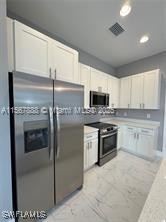 426 Mercedes Ct, Lehigh Acres, FL 33972 - kitchen with appliances with stainless steel finishes, recessed lighting, light marble finish flooring, and white cabinetry