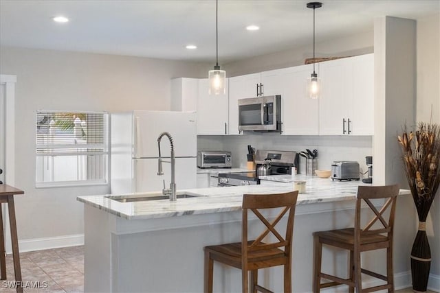 51-55 Lake St, North Fort Myers, FL 33903 - kitchen with appliances with stainless steel finishes, a peninsula, tasteful backsplash, light stone counters, and hanging light fixtures