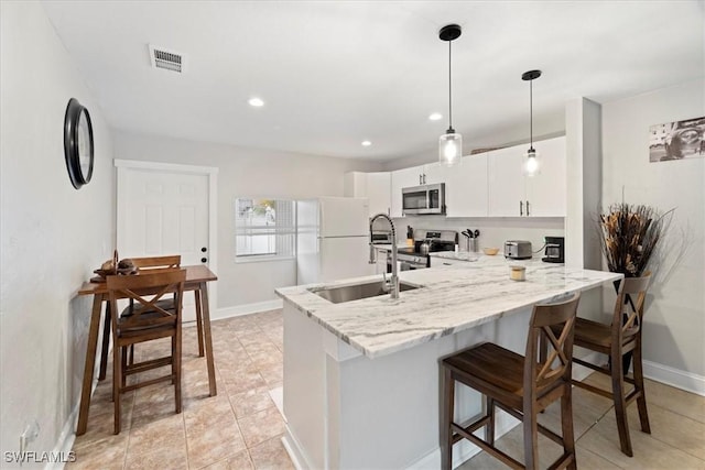 51-55 Lake St, North Fort Myers, FL 33903 - kitchen with stainless steel appliances, a peninsula, a sink, white cabinetry, and a breakfast bar