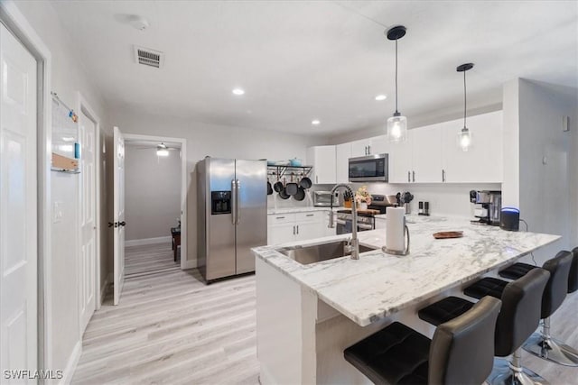 51-55 Lake St, North Fort Myers, FL 33903 - kitchen featuring appliances with stainless steel finishes, a peninsula, light wood-type flooring, white cabinets, and light stone countertops