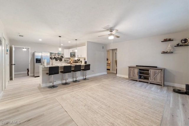 51-55 Lake St, North Fort Myers, FL 33903 - kitchen featuring appliances with stainless steel finishes, white cabinets, a kitchen bar, light countertops, and light wood-style flooring