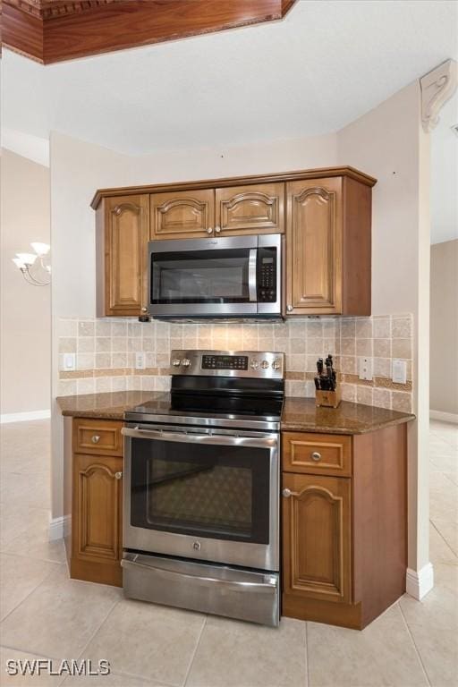 8375 Whisper Trace Ln Unit M203, Naples, FL 34114 - kitchen with stainless steel appliances, dark stone counters, decorative backsplash, and brown cabinets