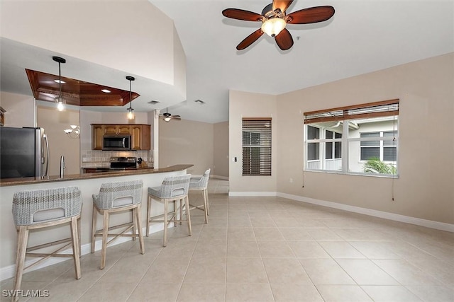 8375 Whisper Trace Ln Unit M203, Naples, FL 34114 - kitchen featuring appliances with stainless steel finishes, a ceiling fan, a raised ceiling, dark countertops, and tasteful backsplash
