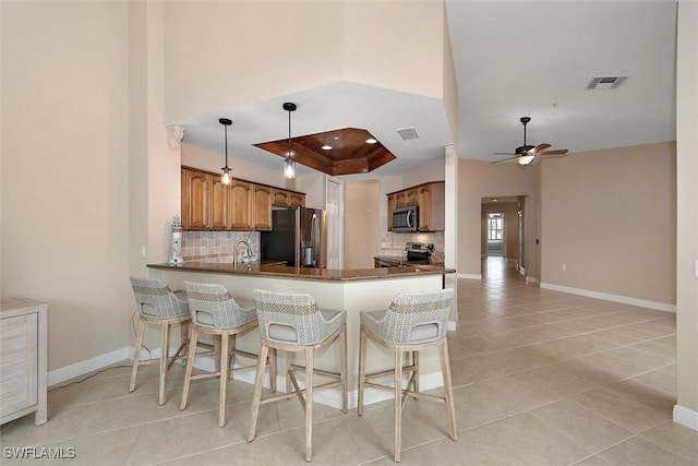 8375 Whisper Trace Ln Unit M203, Naples, FL 34114 - kitchen featuring appliances with stainless steel finishes, backsplash, a tray ceiling, and brown cabinetry